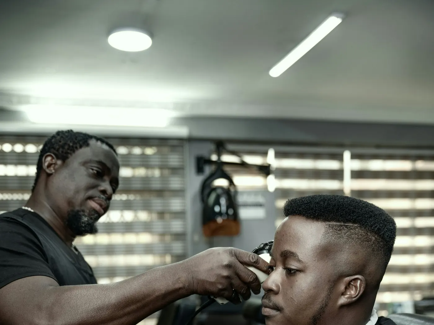 Barber trimming a client's hairline with precision clippers
